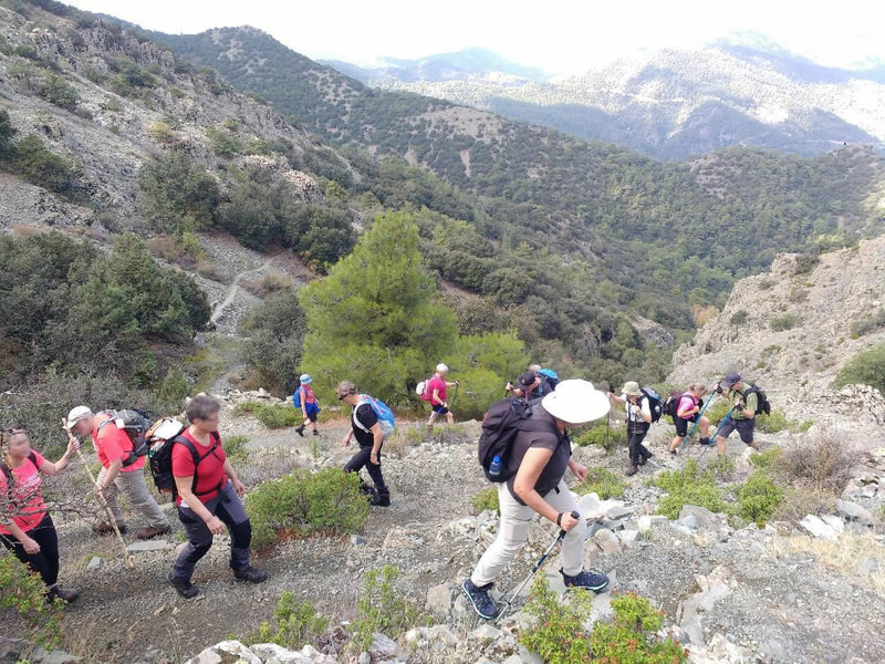 Many walkers ascending a peak  on a zig zag trail