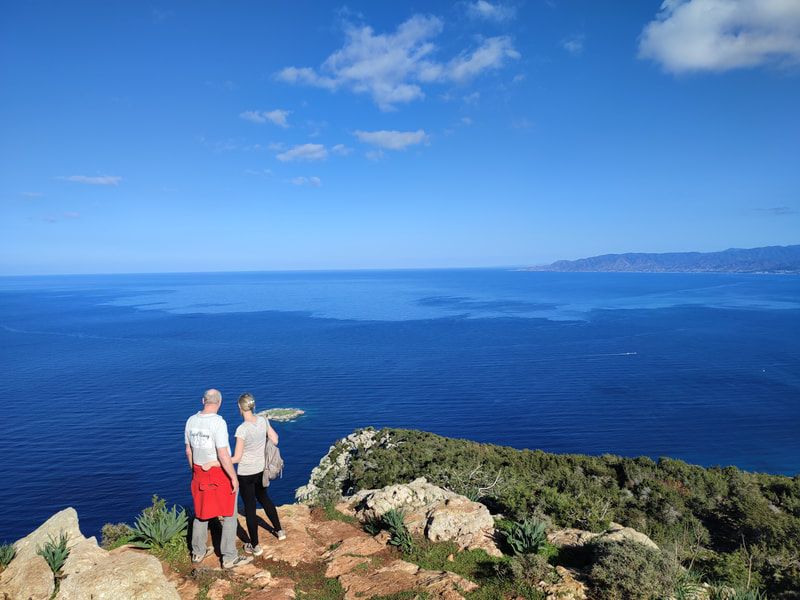 Two walkers standing on a peak, blue sky