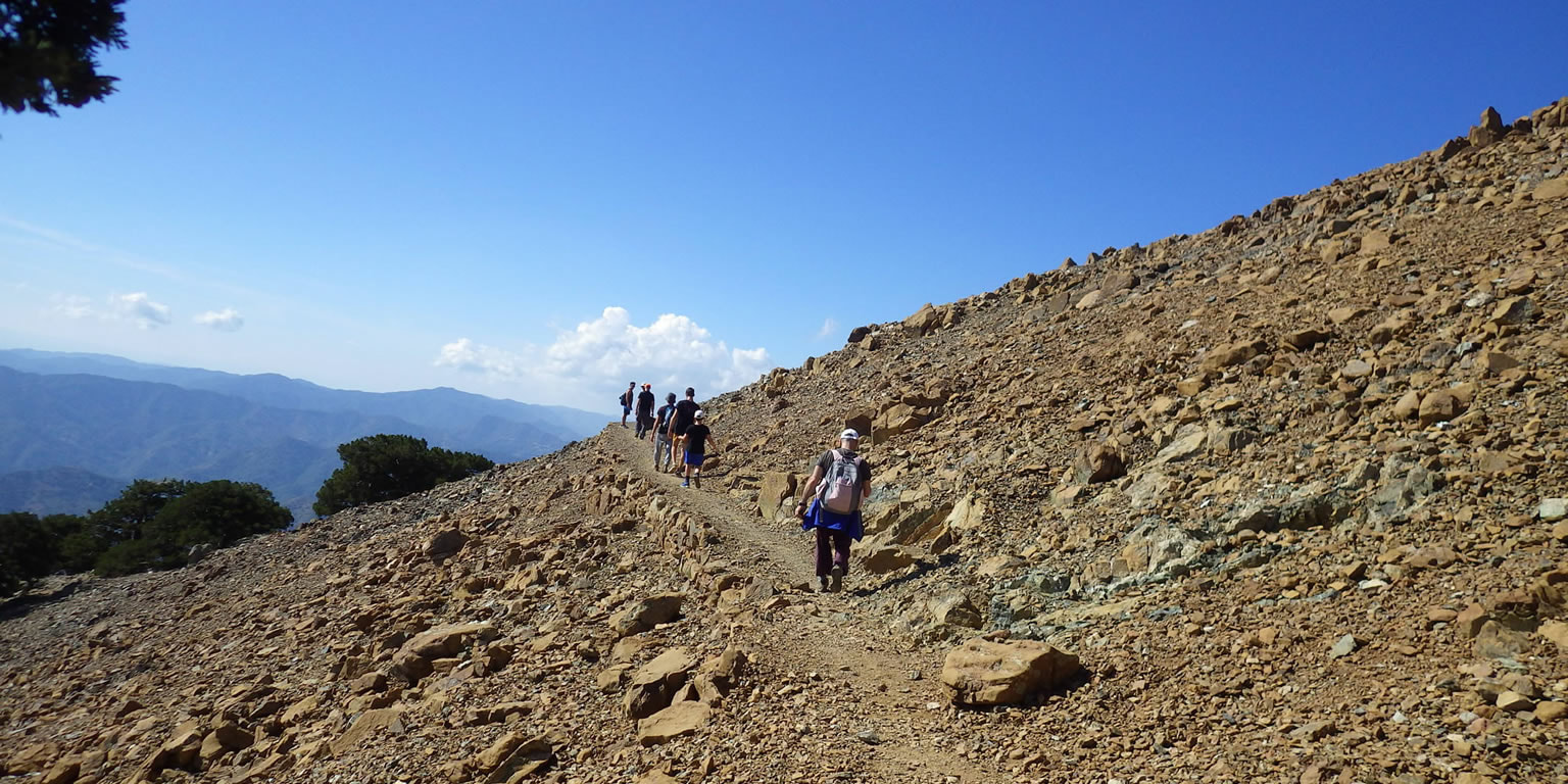 Walkers on a trail on a barren peak slope
