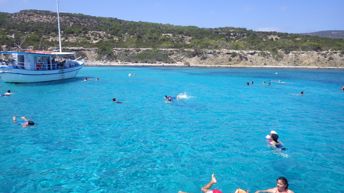 A boat and swimmers in crystal clear light blue waters